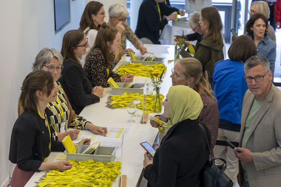 Preisverleihung Integrationspreis des Landes Baden-Württemberg Gäste melden sich an Empfangstisch für Veranstaltung an. Auf dem Tisch liegen Gästeliste und Lanyards.