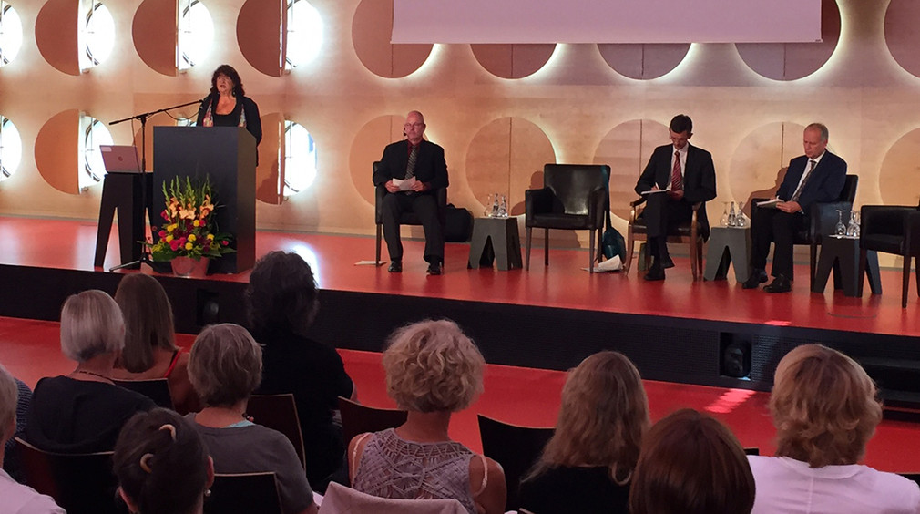 Staatssekretärin Bärbl Mielich steht an Redepult auf einer Bühne