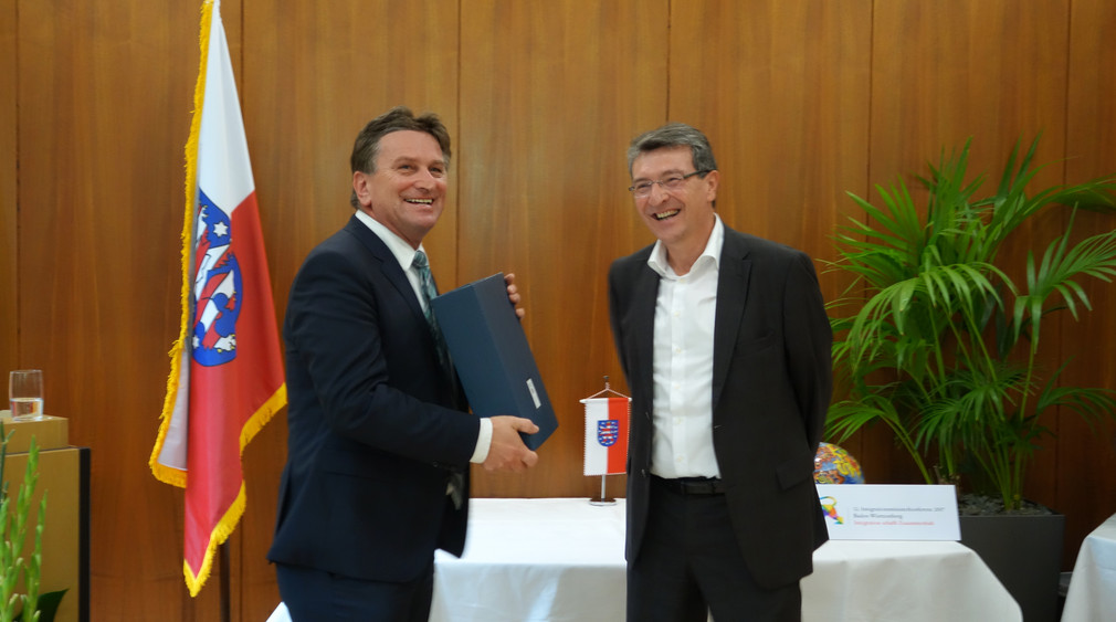 Sozial- und Integrationsminister Manne Lucha überreicht Thüringens Migrationsminister Dieter Lauinger als Präsent Wein vom Staatsweingut Meersburg.