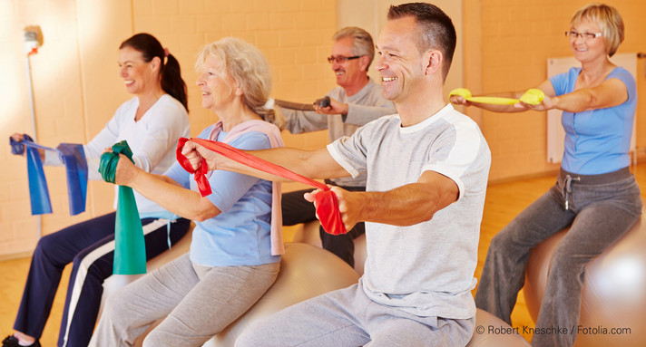 Frauen und Männer machen Übungen mit Gymnastikband