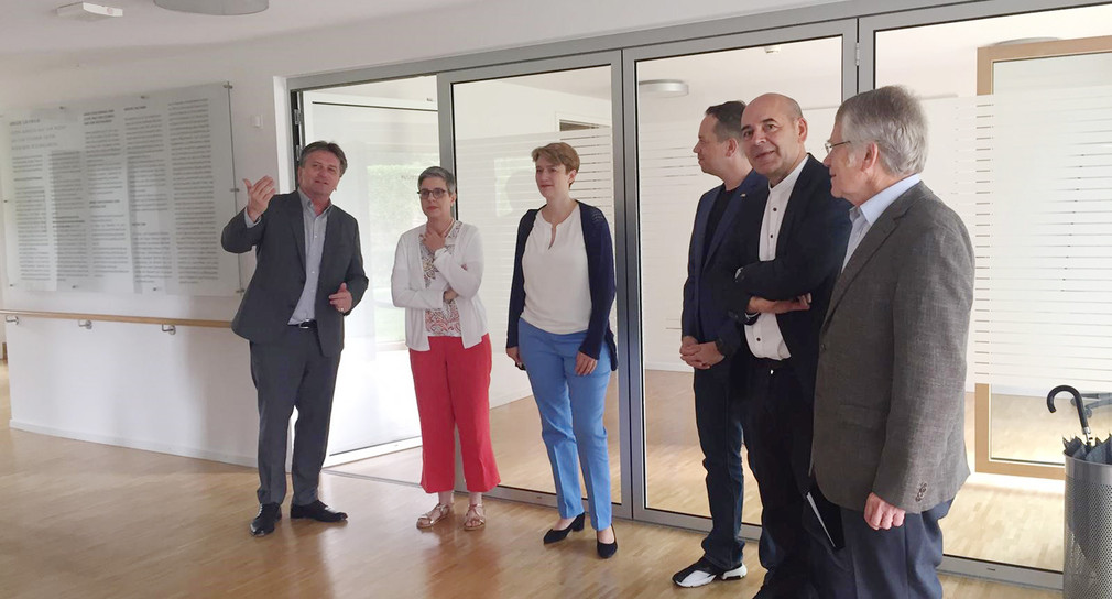 Minister Manne Lucha und die Esslinger Landtagsabgeordnete Andrea Lindlohr stehen mit der Leiterin des Hospiz Esslingen in dessen Eingangsbereich