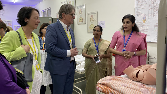 Minister Manne Lucha spricht bei einer Führung durch das Ferguson College der Deccan Education Society (DES) in Pune mit Mitarbeitenden, im Hintergrund hängen medizinische Poster an der Wand.