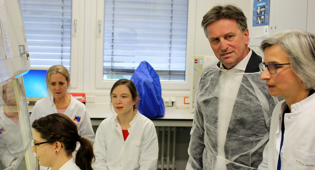 Gesundheitsminister Manne Lucha steht mit anderen Besuchenden im Labor im Landesgesundheitsamt Baden-Württemberg