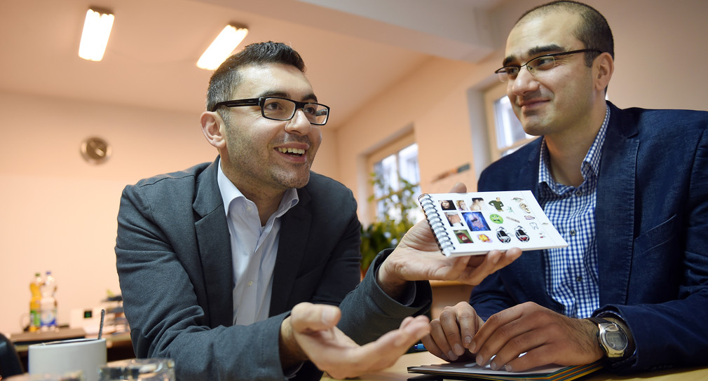 Yalcin Bayraktar und Mehmet Aksoyan vom türkischen Verein TAVIR zeigen Willkommenskarten, die Flüchtlinge bekommen sollen, damit ihnen die Integration und Verständigung besser gelingt. (Foto: Felix Kästle/dpa)