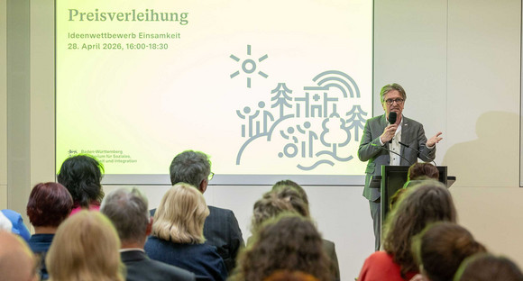 Sozialminister Manne Lucha steht vor Publikum und spricht in Mikrofon.