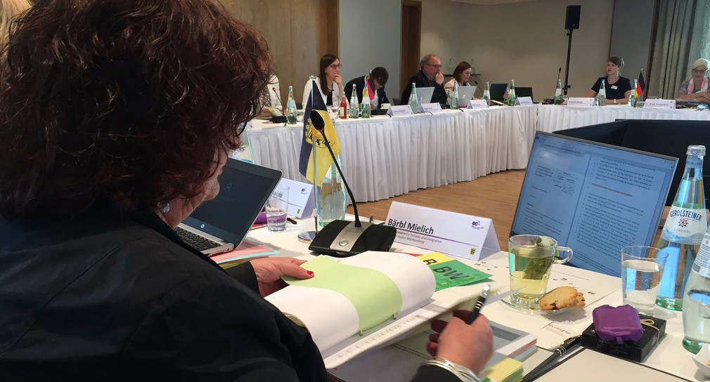Staatssekretärin Bärbl Mielich blättert an Konferenztisch durch eine Akte