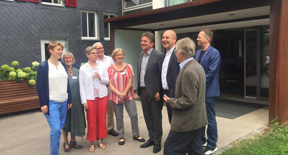 Minister Manne Lucha steht mit Mitarbeitenden und Ehrenamtlichen des Hospiz Esslingen vor dem Gebäude