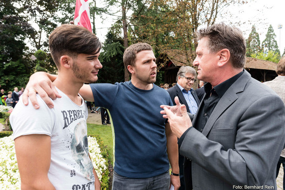 Sozial- und Integrationsminister Manne Lucha unterhält sich mit zwei jungen Männern