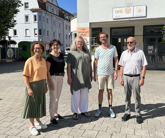 Staatssekretärin Dr. Ute Leidig beim Gruppenbild mit Mitarbeitenden der Tafel. Das Foto wurde vor den Räumen der Tafel im Freien aufgenommen.