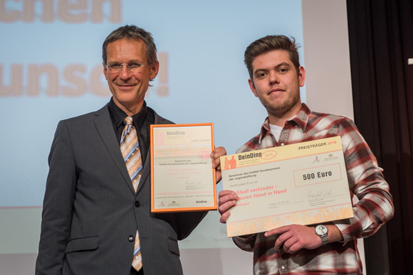 Ministerialdirektor Wolf Hammann und ein Schüler des Johannes-Kepler-Gymnasiums auf der Bühne