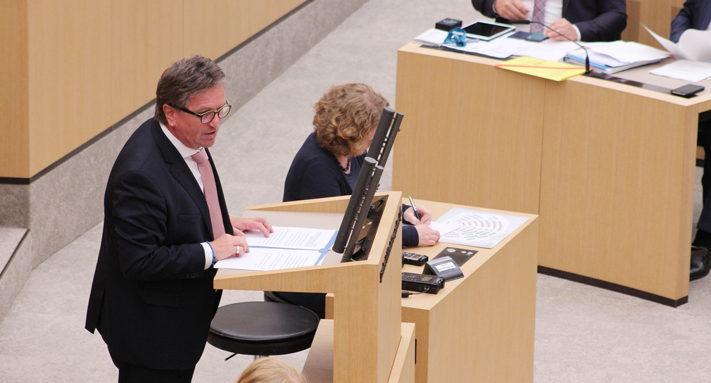 Minister Manne Lucha steht an Redepult im Landtag von Baden-Württemberg