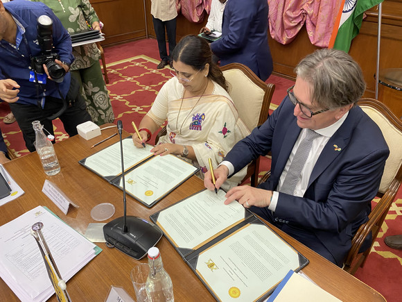 Minister Manne Lucha und Staatsministerin Madhuri Misal des indischen Bundesstaats Maharashtra sitzen nebeneinander an einem Tisch und unterzeichnen Dokumente.