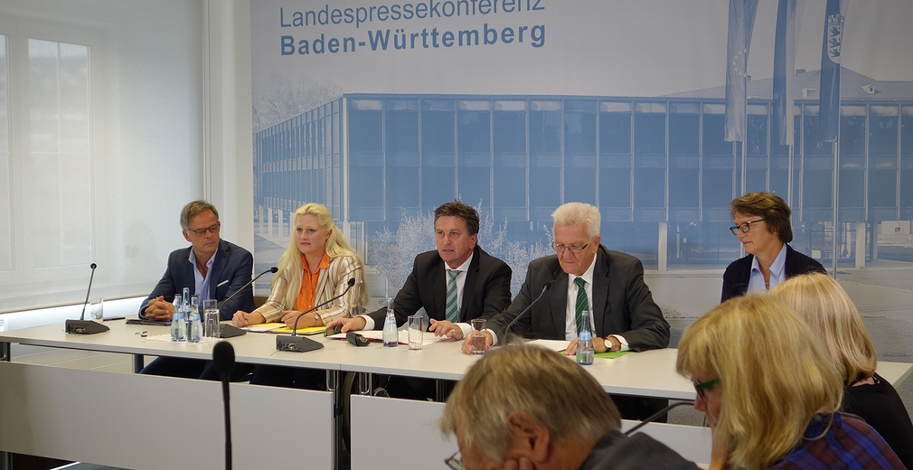 Blick auf das mit Stephanie Aeffner, Manne Lucha und Winfried Kretschmann besetzte Podium der Regierungspressekonferenz