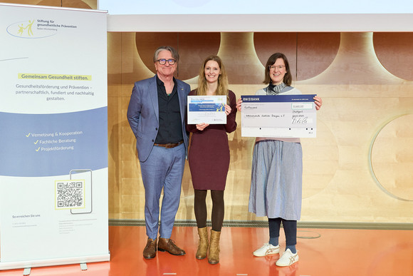 Preisverleihung des Präventionspreises: Minister Manne Lucha übergibt Scheck und Urkunde an Preisträger Volkshochschule Südlicher Breisgau.
