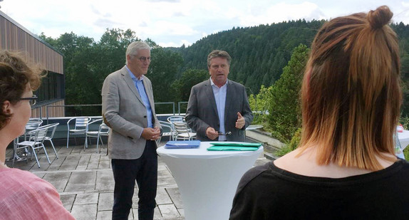 Minister Manne Lucha spricht auf einer Terrasse mit Calwer Landrat Helmut Riegger und Mitarbeiterinnen des Frauenhauses Calw