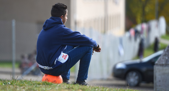 Ein jugendlicher Asylbewerber sitzt vor der Landeserstaufnahmestelle in Meßstetten (Baden-Württemberg) auf einem Ball.