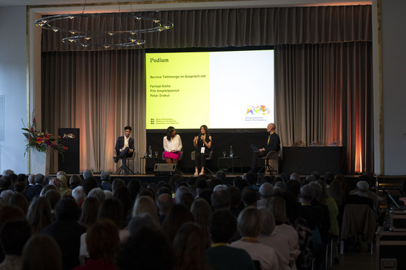 Preisverleihung Integrationspreis des Landes Baden-Württemberg Podiumsdiskussion mit Farhad Alsilo, Pim Ampikitpanich und Petar Drakul auf der Bühne, moderiert von Bernice Tshimanga.