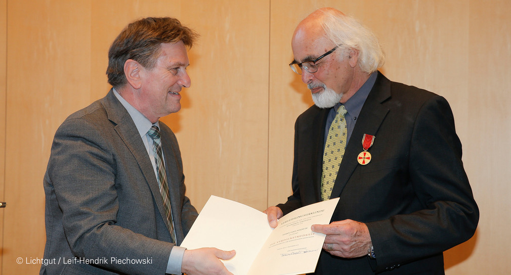 Sozial- und Integrationsminister Manne Lucha überreicht Jama Maqsudi die vom Bundespräsidenten verliehene Verdienstmedaille des Verdienstordens der Bundesrepublik Deutschland.