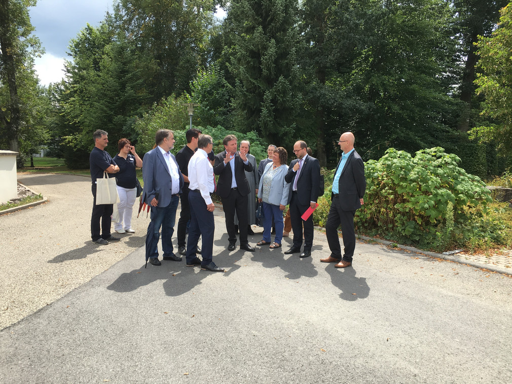 Minister Manne Lucha umringt von einer Personengruppe auf dem Gelände der Stiftung St. Franziskus in Schramberg-Heiligenbronn