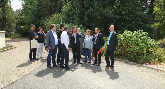 Minister Manne Lucha umringt von einer Personengruppe auf dem Gelände der Stiftung St. Franziskus in Schramberg-Heiligenbronn