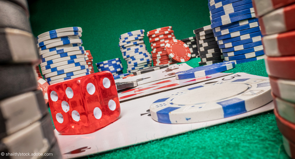 Pokerchips, Spielwürfel und Spielkarten liegen auf einem Tisch.