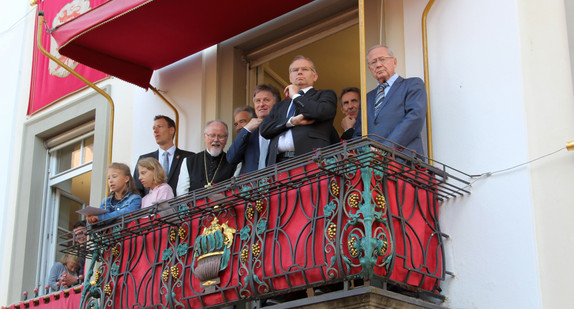 Sozialminister Manne Lucha steht mit weiteren Zuschauern auf dem Rathausbalkon der Stadt Weingarten.