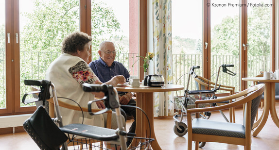 Seniorenpaar sitzt an Cafeteriatisch im Pflegeheim