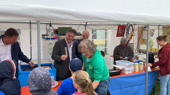 Minister Manne Lucha steht im Freien an einer Büffet-Theke und verteilt Eis an Kinder. 