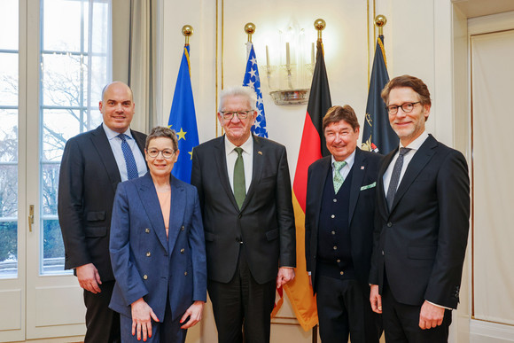 Internationales Kretschmann trifft AmCham Germany von links nach rechts: Daniel Andrich (AmCham Germany), Sabine Menne (Präsidentin AmCham Germany), Ministerpräsident Winfried Kretschmann, Prof. Dr. Gerhard Wegen (Chairman AmCham Baden-Württemberg), und Staatsminister Dr. Florian Stegmann stehen vor Fahnen.