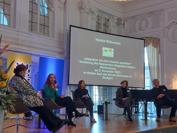 Podiumsdiskussion mit einzelnen Strategiegruppenmitgliedern des Netzwerkes Integration auf einer Bühne.