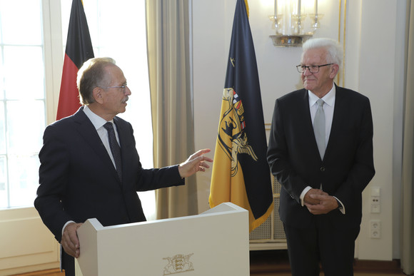 Wirtschaft Kretschmann ehrt Franz Fehrenbach Franz Fehrenbach (links) und Ministerpräsident Winfried Kretschmann (rechts) stehen stehen im Runden Saal der Villa Reitzenstein vor Fahnen.