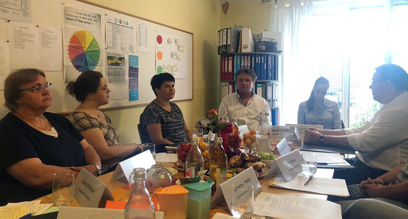 Minister Manne Lucha sitzt mit Mitarbeitenden des Präventionsnetzwerks Ortenaukreis an einem Besprechungstisch