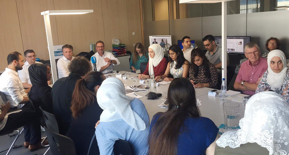 Minister Manne Lucha sitzt mit Redaktionsmitgliedern des integrativen Medienprojekts „tünews INTERNATIONAL“ in Tübingen an einem Besprechungstisch