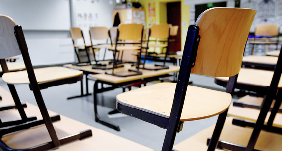 Stühle stehen in leerem Klassenzimmer auf den Tischen.