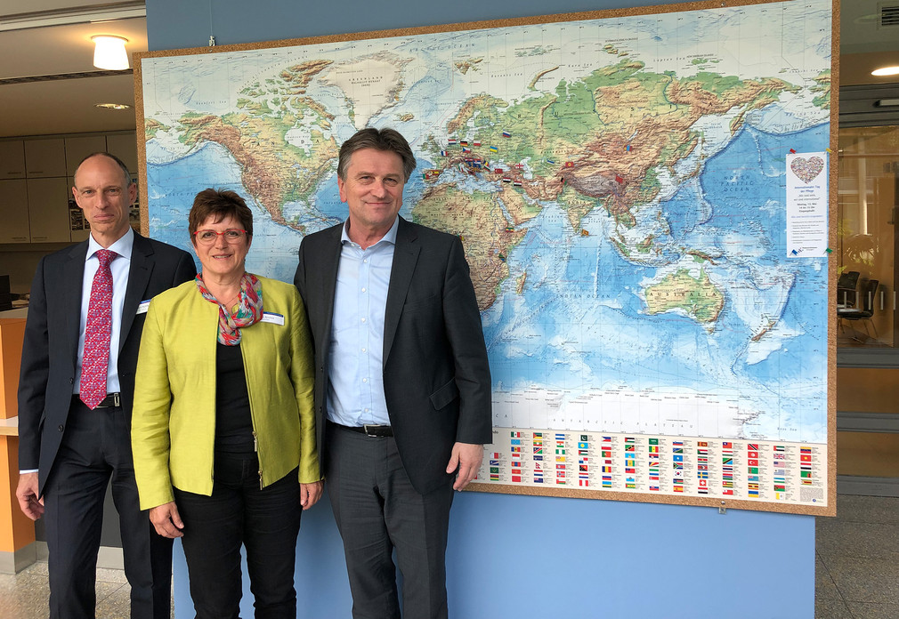 Geschäftsführer Herr Bernd Rühle, Pflegedirektorin Frau Elke Reinfeld und Minister Manne Lucha stehen vor einer Weltkarte