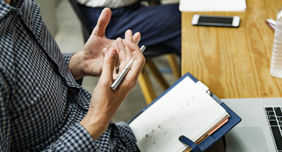 Mann mit Stift in der Hand bei Team-Besprechung