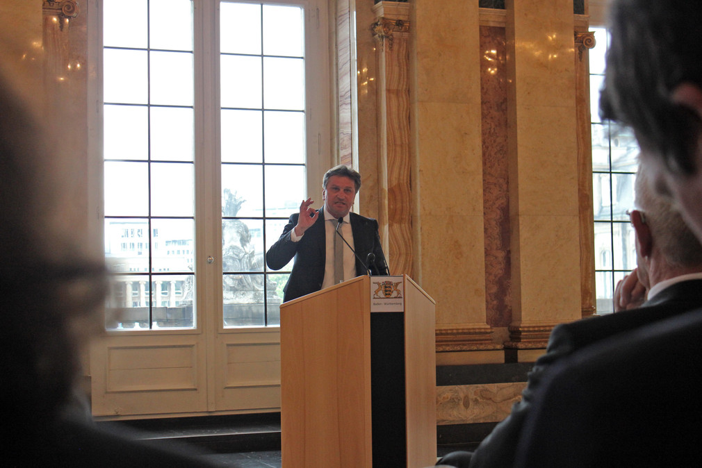 Sozial- und Integrationsminister Manne Lucha spricht an Redepult im Marmorsaal im Neuen Schloss in Stuttgart