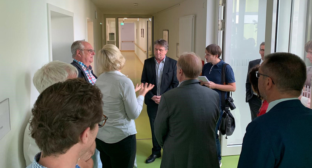 Minister Manne Lucha unterhält sich auf Wohnungsflur mit Mitarbeitenden der Therapeutischen Wohngruppe Ehingen