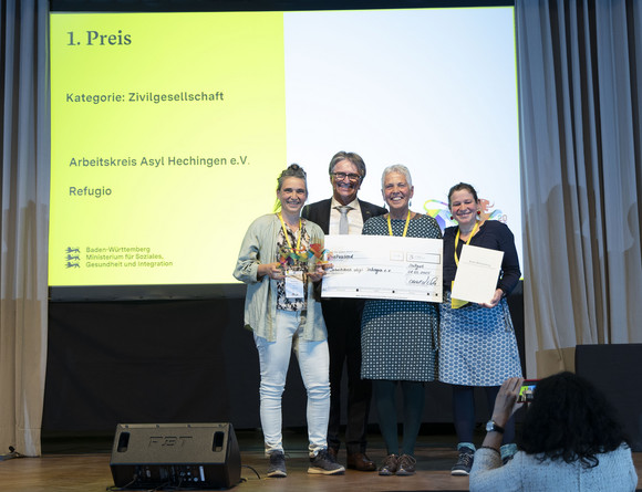 Preisverleihung Integrationspreis des Landes Baden-Württemberg Gruppenfoto der Preisträger von Platz 1 der Kategorie „Zivilgesellschaft“ mit Minister Manne Lucha auf Bühne.