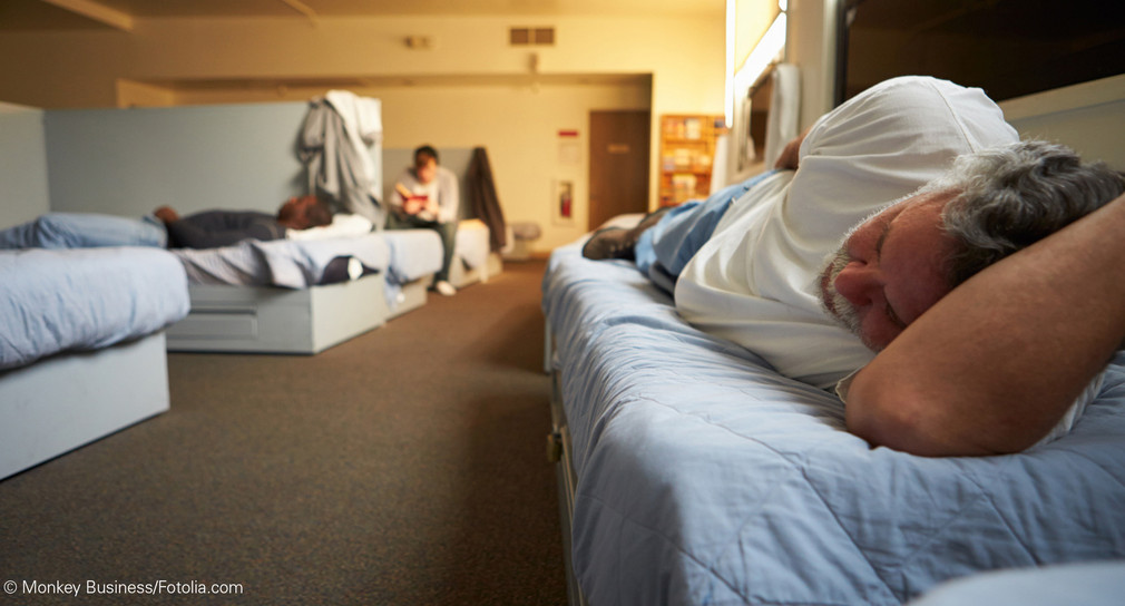 Mann schläft auf Bett in einem Obdachlosenheim