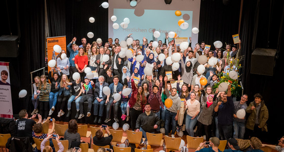 Gruppenfoto aller Preisträger des Jugendbildungspreises DeinDing mit Sozial- und Integrationsminister Manne Lucha auf der Bühne des Stuttgarter Jugendhauses Cann