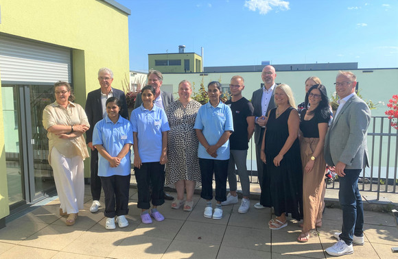 Gruppenfoto im Freien: Minister Lucha und Christian Rauch, Regionaldirektion Baden-Württemberg der Bundesagentur für Arbeit, mit Mitarbeitenden und Verantwortlichen der Einrichtung @PASODI im Paritätische Mehrgenerationenzentrum in Stuttgart