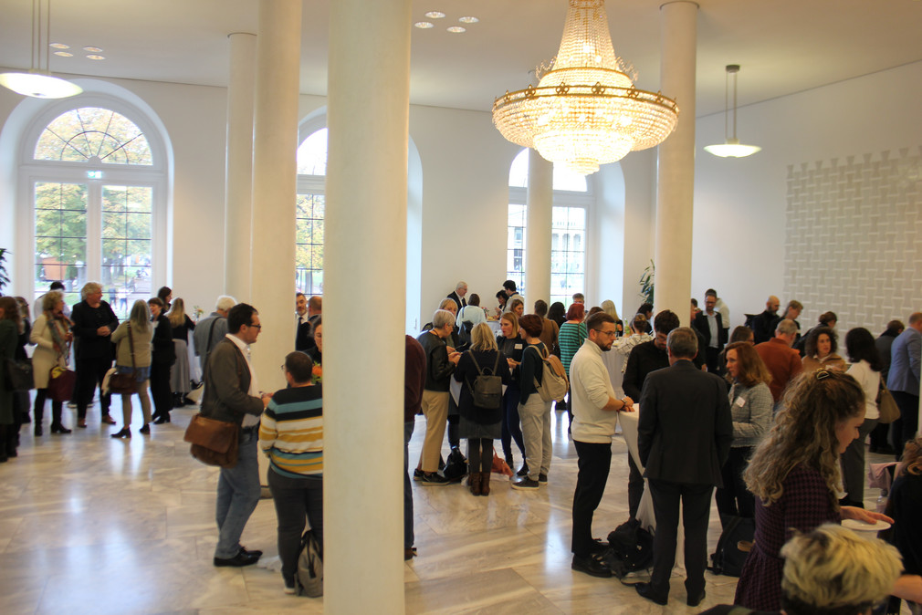 Zum Abschluss der Veranstaltung stehen Teilnehmende in Gruppen im Foyer des Neuen Schlosses zusammen.