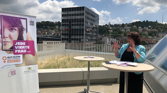 Staatssekretärin Bärbl Mielich steht auf Terrasse des Sozialministerium Baden-Württemberg neben Plakat "Jede vierte Frau"