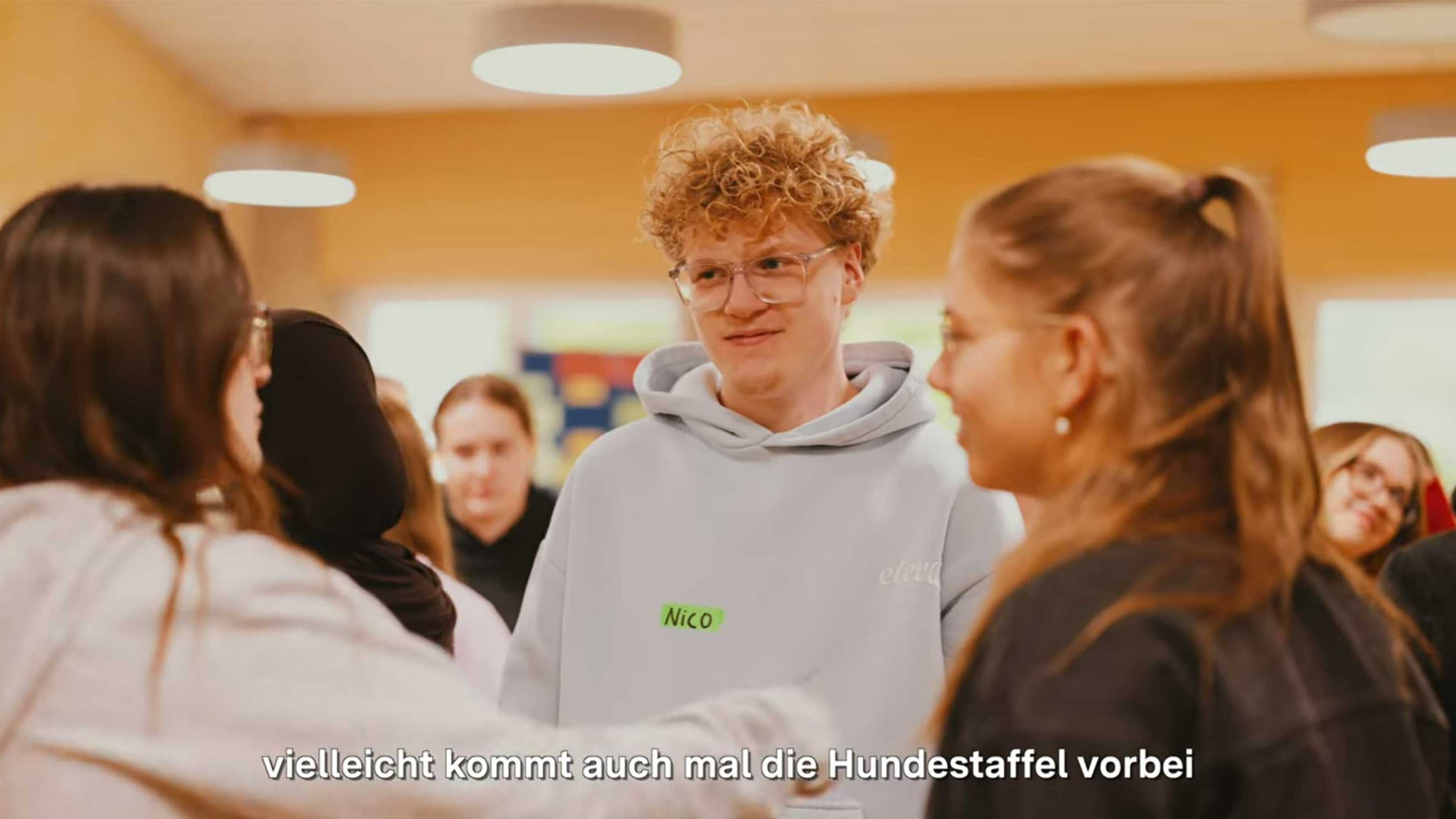 Junge Menschen stehen beim Gespräch zusammen.