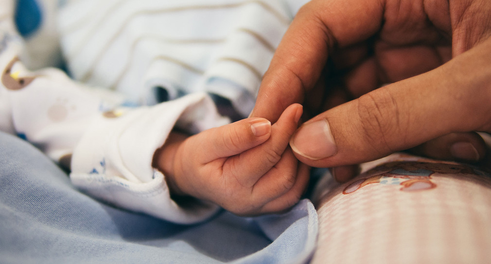 Frauenhand hält Babyhand