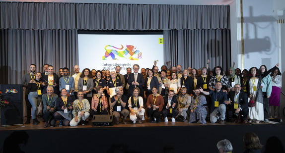 Gruppenfoto aller Preisträger des Integrationspreises 2025 mit Minister Manne Lucha auf Bühne.