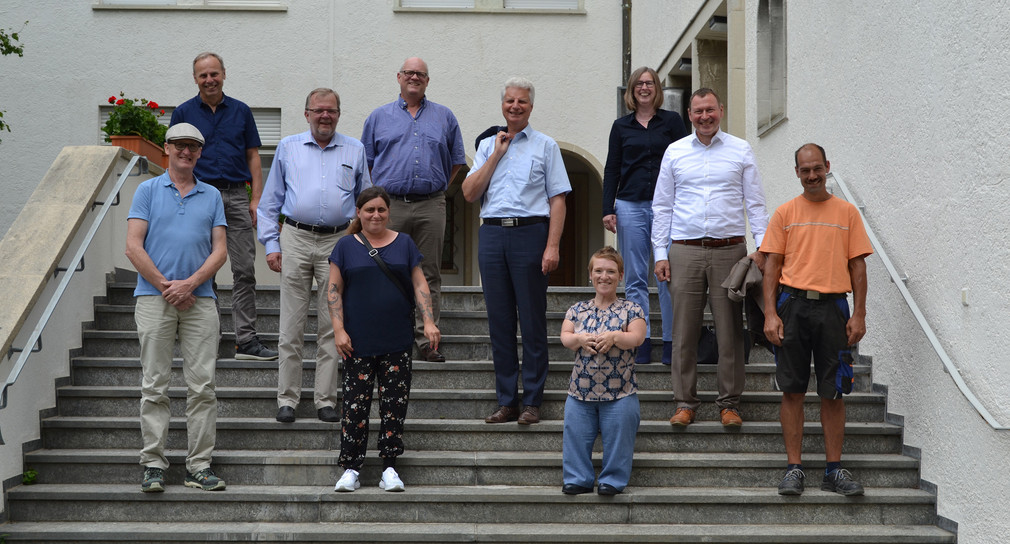 Gruppenfoto auf Treppenstufen: Simone Fischer mit Frauenbeauftragter Melanie Rosenberger und Werkstattrat Andreas Grimm, den Vorständen der Stiftung Liebenau Prälat Michael Brock und Berthold Broll, der Geschäfts-führung Elke Gundel und Jörg Munk. 
