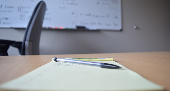 Kugelschreiber und Notizblock liegen auf einem Schreibtisch