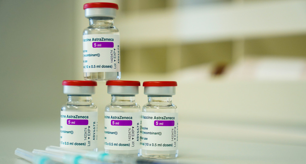 Auf einem Tisch liegen bzw. stehen Spritzen und Ampullen mit dem Covid-19 Impfstoff des schwedisch-britischen Pharmakonzerns AstraZeneca.